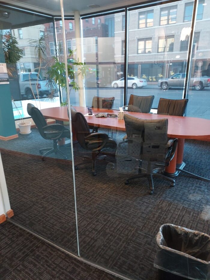 A conference room with large, street-facing windows belonging to 17th and Central Executive Suites.